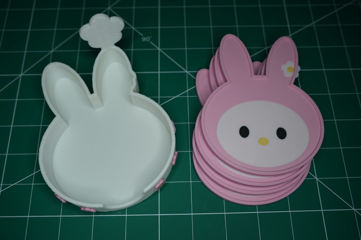The empty white holder beside a stack of four bunny coasters