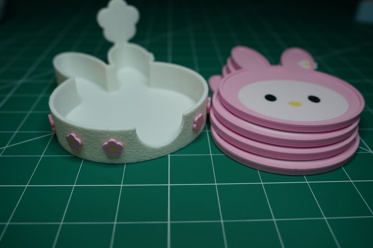 The fuzzy white holder with its pink flower charms, next to the stack