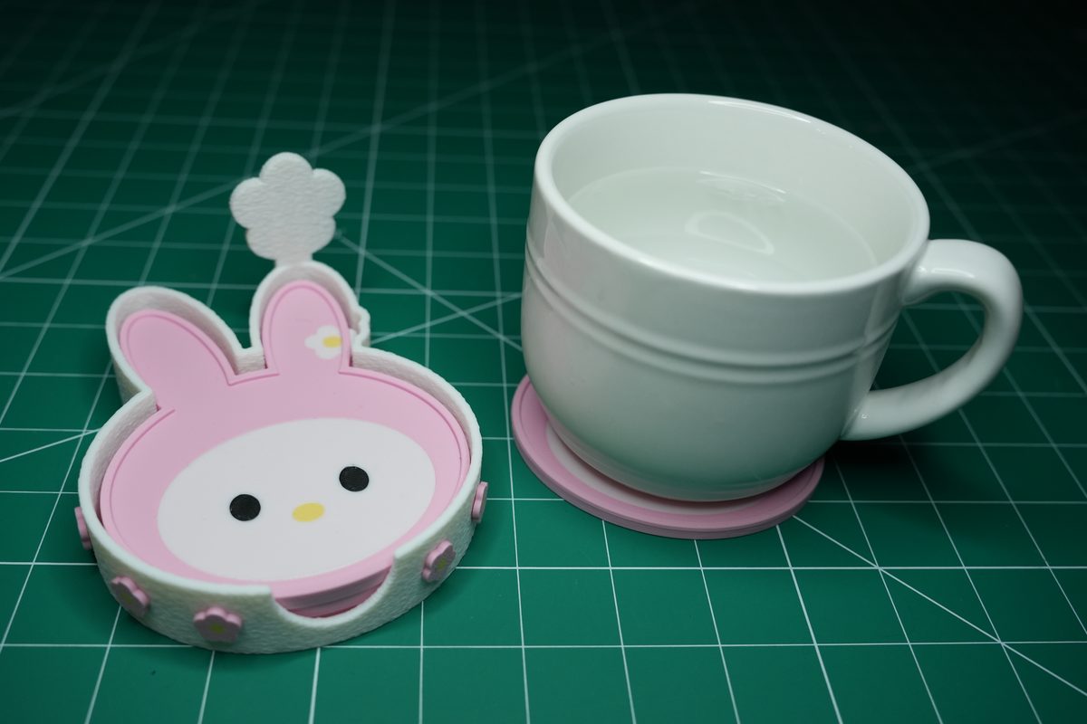 A white mug on a bunny coaster next to the holder