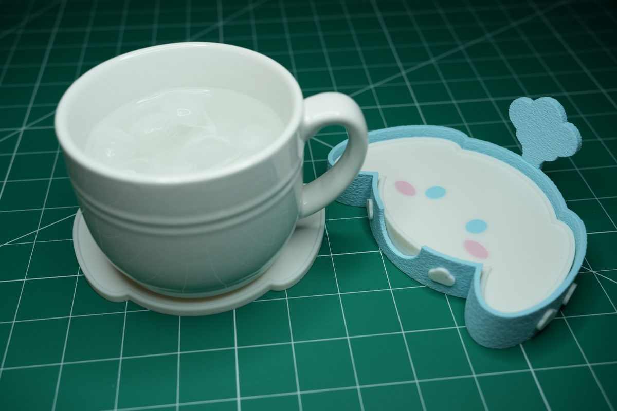 A white mug of water sitting on a puppy coaster next to the holder