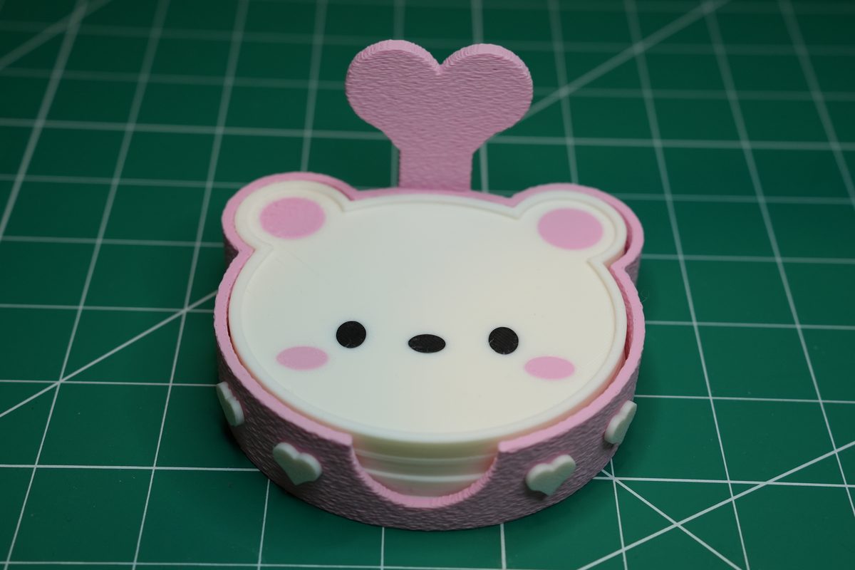 A white bear coaster sitting in its pink holder, a pink heart on the back wall