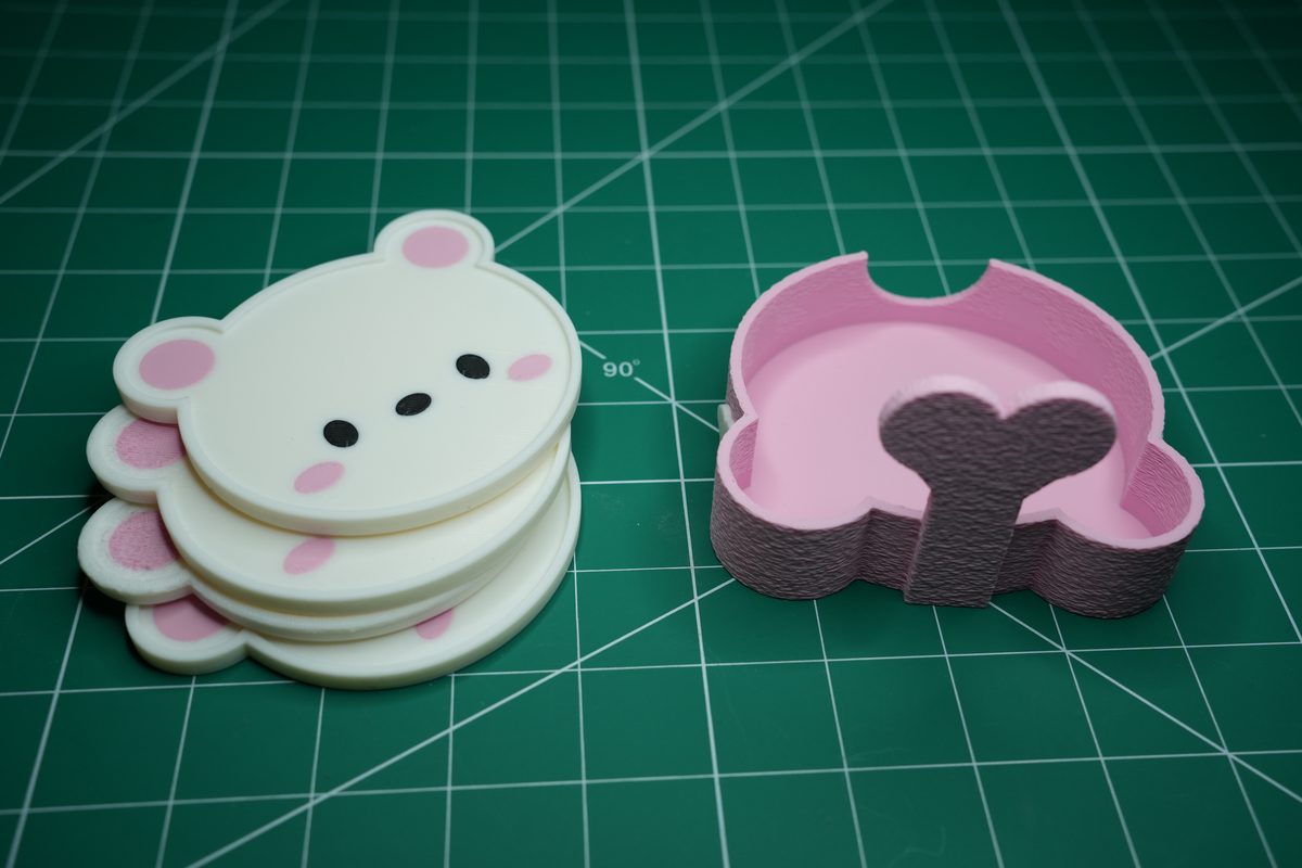 Four white bear coasters stacked beside the empty pink holder